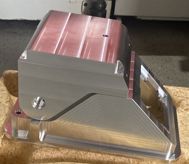 Gefrästes Aluminiumteil mit Rippen und Schrägen, die Oberseite noch mit Schutzfolie beklebt